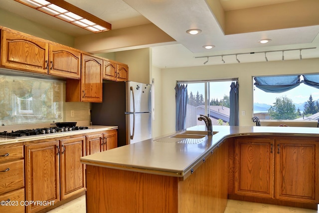 kitchen featuring backsplash, appliances with stainless steel finishes, sink, an island with sink, and rail lighting