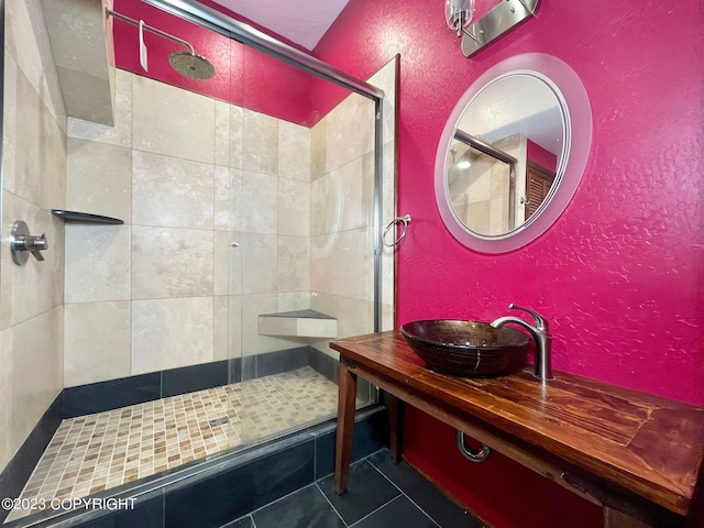 bathroom with tile flooring, a shower with shower door, and vanity with extensive cabinet space