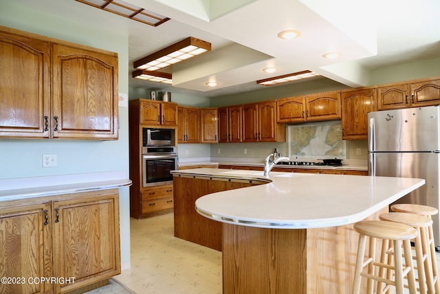 kitchen with tasteful backsplash, a center island with sink, a kitchen bar, stainless steel appliances, and light tile flooring