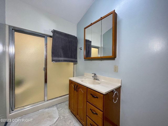 bathroom featuring an enclosed shower, vanity, tile floors, and vaulted ceiling