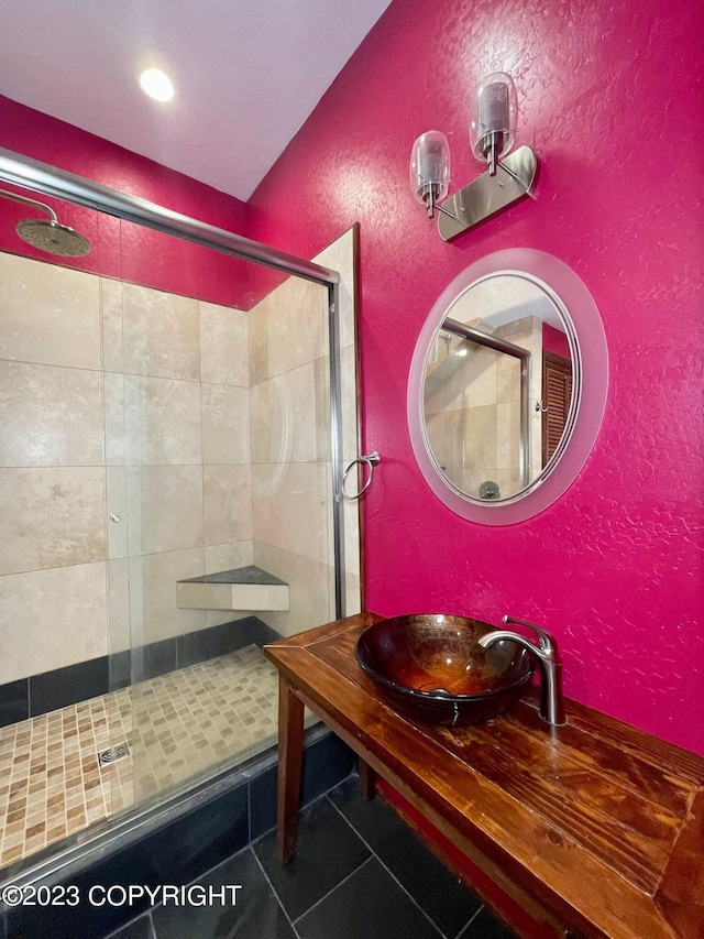 bathroom featuring sink, a shower with door, and tile flooring