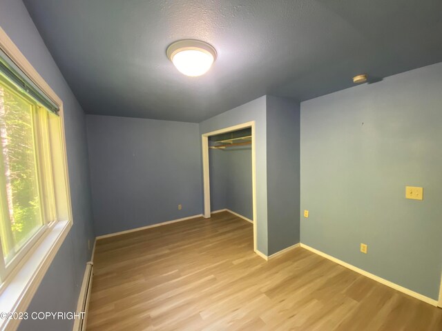 unfurnished bedroom featuring a closet, multiple windows, and light hardwood / wood-style floors