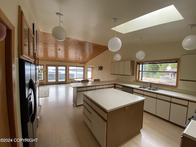 kitchen featuring decorative light fixtures, a center island, black fridge, sink, and white cabinetry