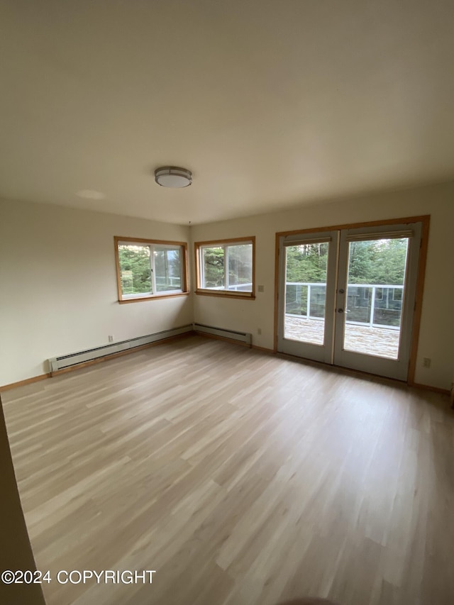 empty room with a baseboard radiator and light hardwood / wood-style floors