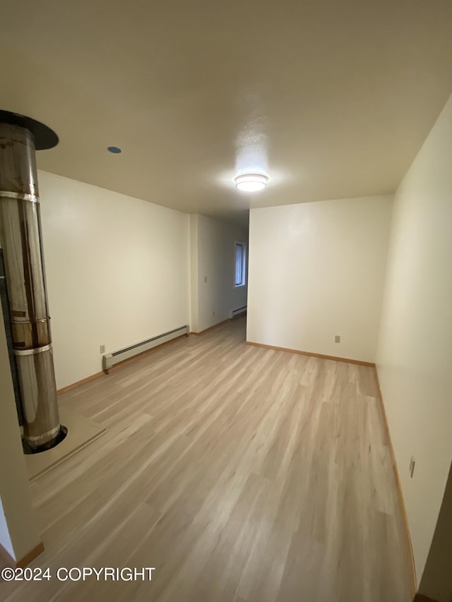 basement featuring a baseboard heating unit and light hardwood / wood-style floors