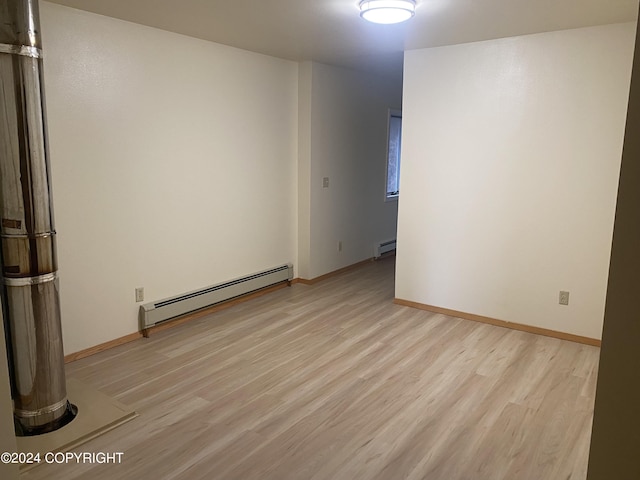 spare room featuring baseboard heating and light hardwood / wood-style flooring