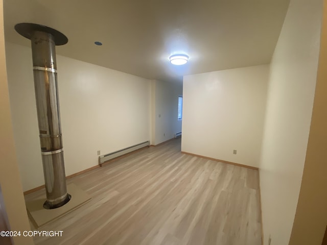 basement featuring light wood-type flooring and baseboard heating