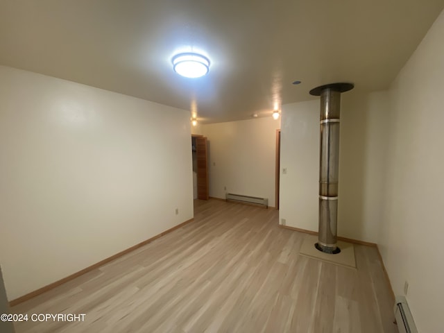 basement featuring light wood-type flooring and baseboard heating
