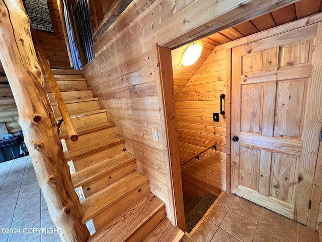 stairs featuring tile patterned flooring and wood walls