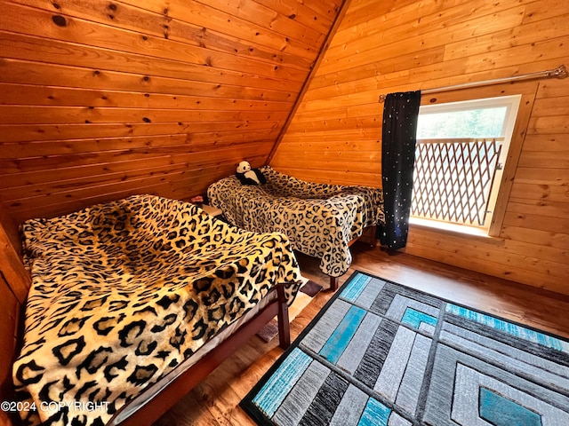 bedroom with hardwood / wood-style flooring, vaulted ceiling, wooden ceiling, and wooden walls