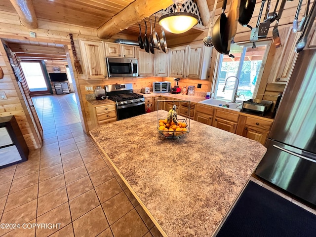 kitchen featuring appliances with stainless steel finishes, sink, light tile patterned floors, wooden ceiling, and beam ceiling