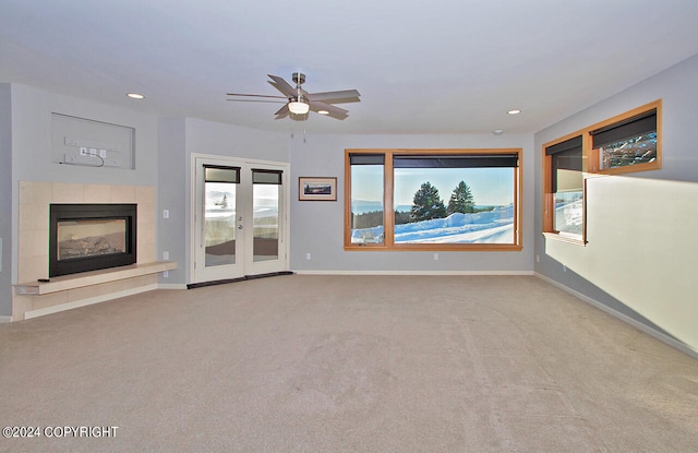 unfurnished living room featuring ceiling fan, light colored carpet, and a tile fireplace