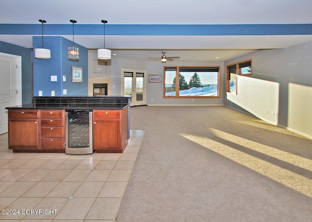 kitchen featuring ceiling fan, wine cooler, light colored carpet, and hanging light fixtures