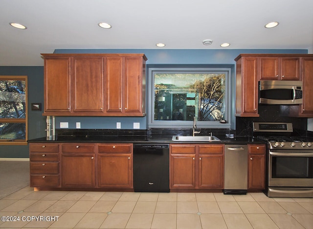 kitchen featuring sink, dark stone countertops, appliances with stainless steel finishes, and light tile patterned floors