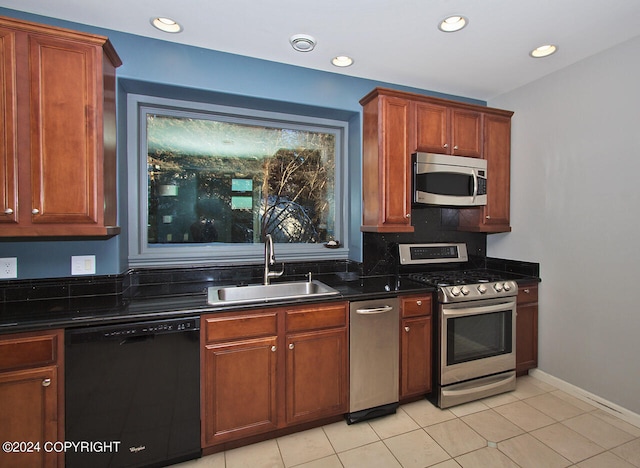 kitchen with stainless steel appliances, decorative backsplash, sink, light tile patterned floors, and dark stone counters