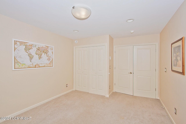 unfurnished bedroom featuring a closet and light colored carpet