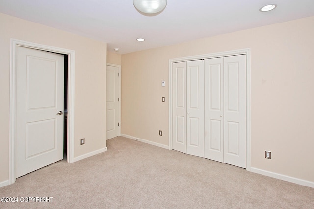 unfurnished bedroom featuring light carpet and a closet