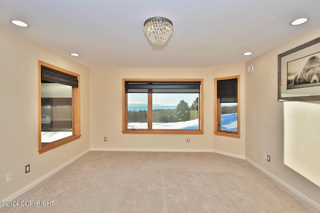 empty room featuring a notable chandelier and light carpet