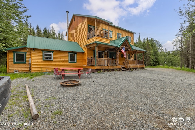 back of house with an outdoor fire pit and a balcony