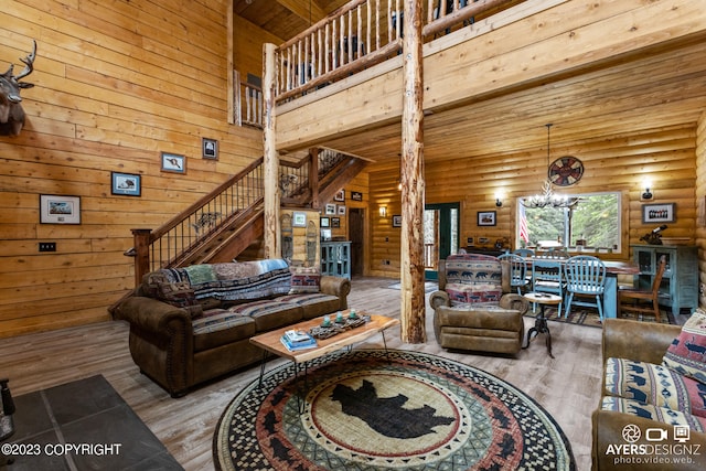 living room with an inviting chandelier, light hardwood / wood-style floors, log walls, and a towering ceiling