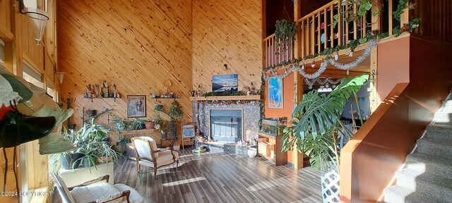 9450 Keshon Cir, Wasilla, AK 99654 - living area featuring a glass covered fireplace, a towering ceiling, wood finished floors, wooden walls, and stairway