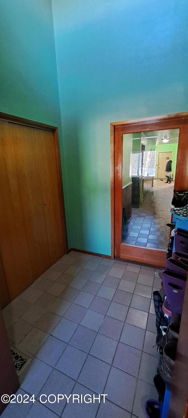 9450 Keshon Cir, Wasilla, AK 99654 - hallway featuring tile patterned floors, a towering ceiling, and baseboards