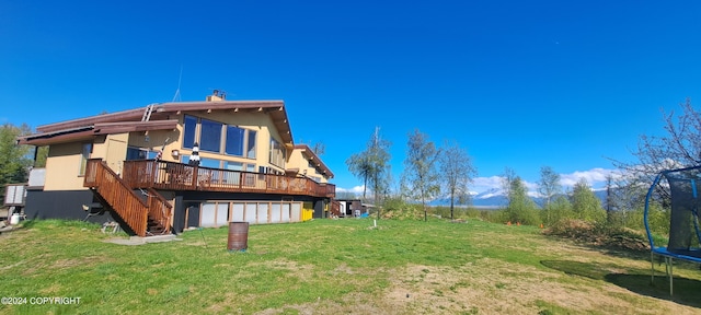 9450 Keshon Cir, Wasilla, AK 99654 - rear view of property featuring a trampoline, a deck, a yard, a garage, and stairs