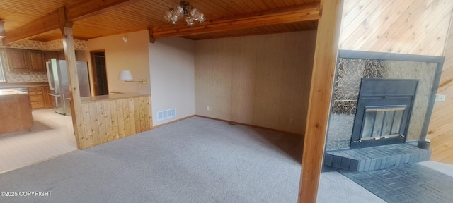 9450 Keshon Cir, Wasilla, AK 99654 - unfurnished living room with a glass covered fireplace, wooden ceiling with exposed beams, light colored carpet, and wooden walls