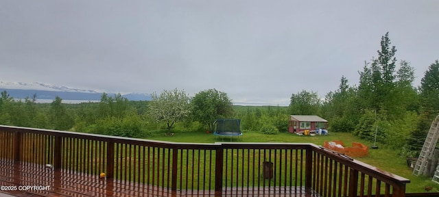 9450 Keshon Cir, Wasilla, AK 99654 - wooden terrace featuring a trampoline, a lawn, and an outbuilding