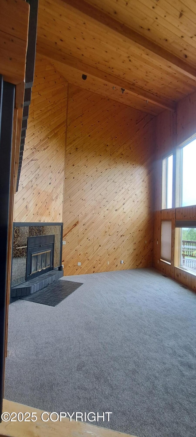 9450 Keshon Cir, Wasilla, AK 99654 - unfurnished living room featuring carpet, wood ceiling, a tiled fireplace, and wood walls