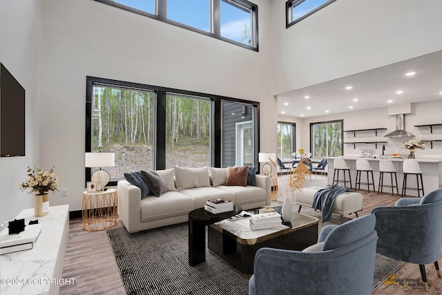 living area featuring wood finished floors, recessed lighting, and a high ceiling