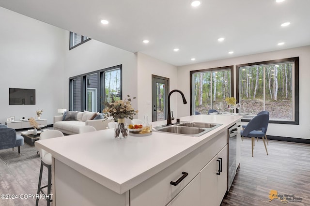 kitchen with a kitchen island with sink, dishwasher, a sink, recessed lighting, and light wood-style flooring