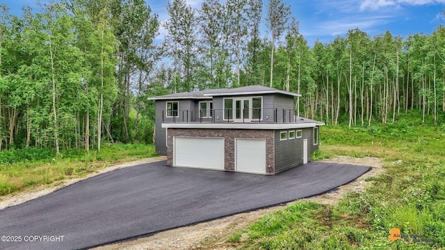 garage with driveway and a wooded view