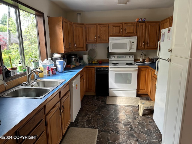 kitchen featuring dark tile flooring, white appliances, and sink