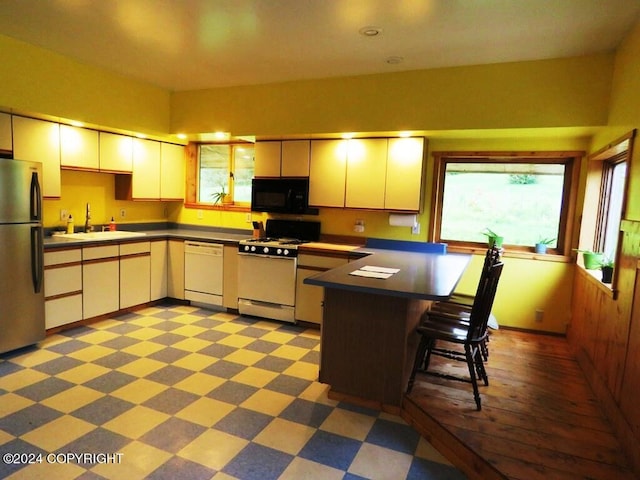 kitchen with white appliances, a kitchen bar, and sink