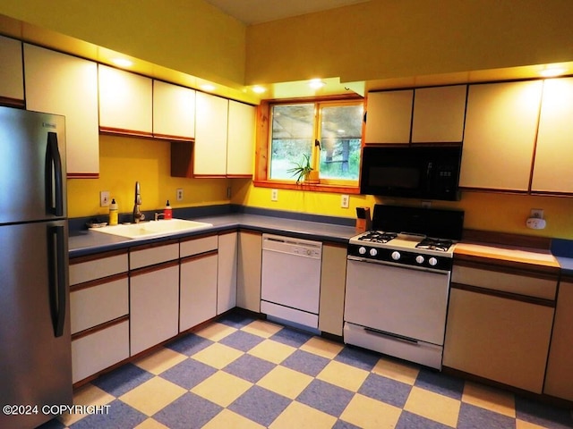 kitchen with white appliances, white cabinetry, and sink