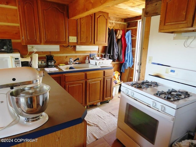 kitchen with light countertops, white appliances, brown cabinetry, and a sink