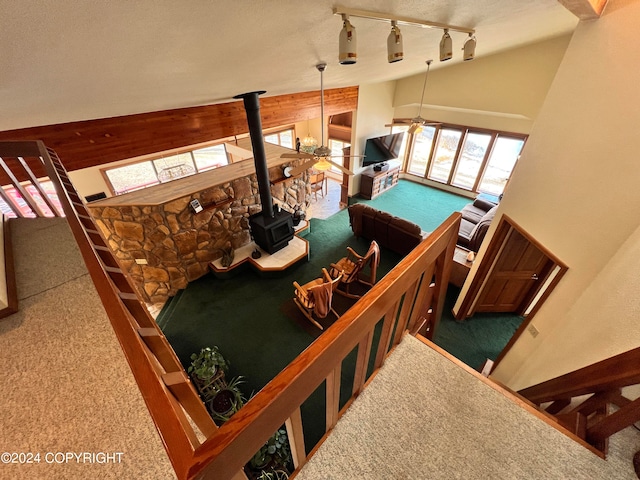 staircase with track lighting, lofted ceiling, carpet flooring, and a wood stove