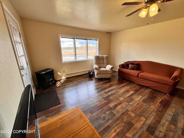 living room featuring hardwood / wood-style flooring, a wood stove, baseboard heating, a textured ceiling, and ceiling fan