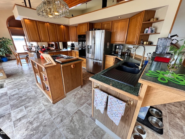 kitchen with a notable chandelier, black double oven, light tile patterned floors, and stainless steel fridge