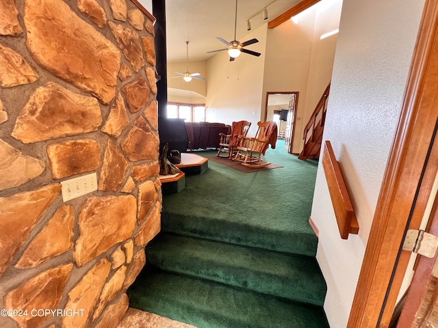 stairway featuring lofted ceiling, carpet, rail lighting, and ceiling fan