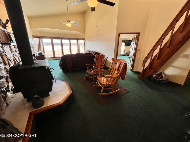 living room with carpet floors, high vaulted ceiling, ceiling fan, and a wood stove