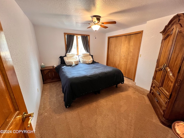 carpeted bedroom with a closet, a textured ceiling, and ceiling fan