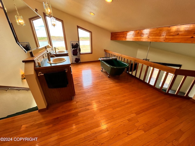 interior space featuring a chandelier, lofted ceiling, sink, and light wood-type flooring