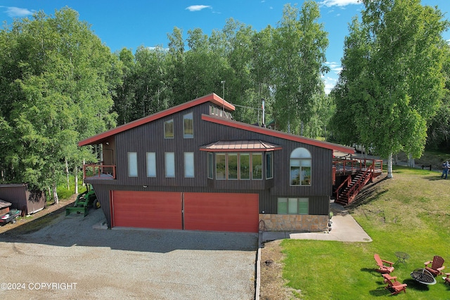 view of front of home with a garage, a deck, and a front yard