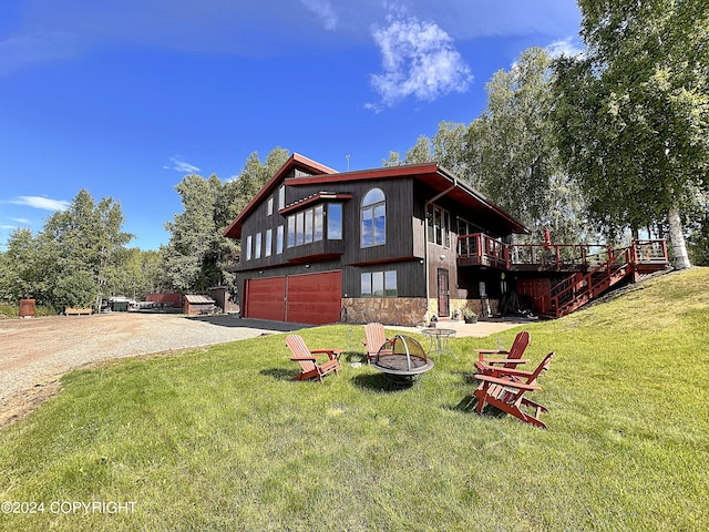 view of front facade featuring a garage, a fire pit, a wooden deck, and a front yard