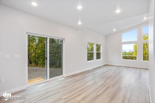 unfurnished room with lofted ceiling and light hardwood / wood-style floors