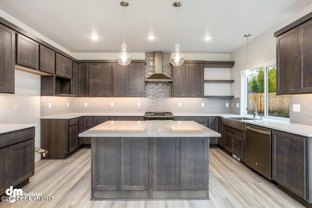 kitchen featuring dark brown cabinetry, pendant lighting, appliances with stainless steel finishes, and wall chimney range hood