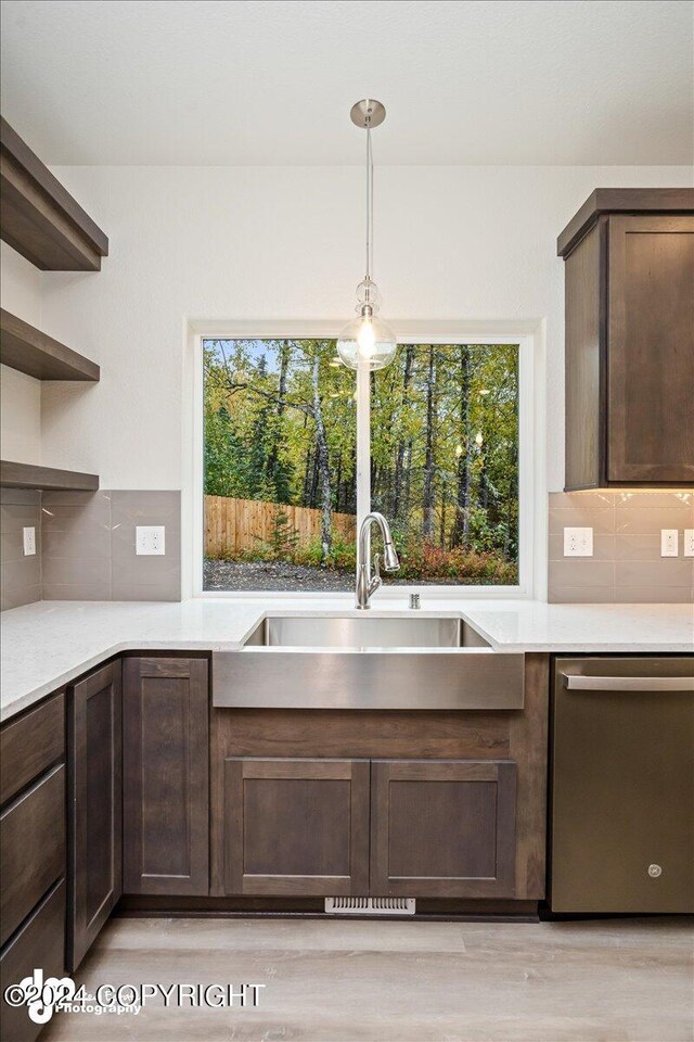 kitchen featuring dishwasher, sink, light hardwood / wood-style flooring, dark brown cabinets, and backsplash