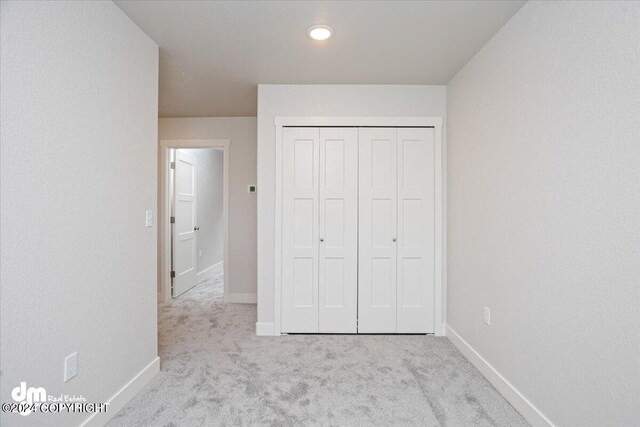 unfurnished bedroom with a closet and light carpet